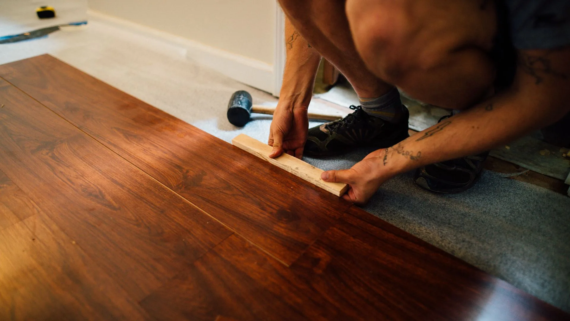 Professional flooring installer laying hardwood floor planks