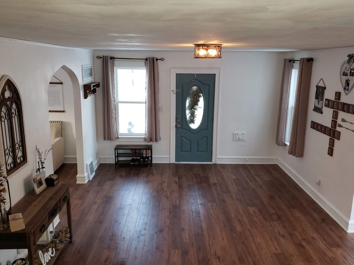 Dark walnut laminate flooring through an entryway and living room with fresh white paint