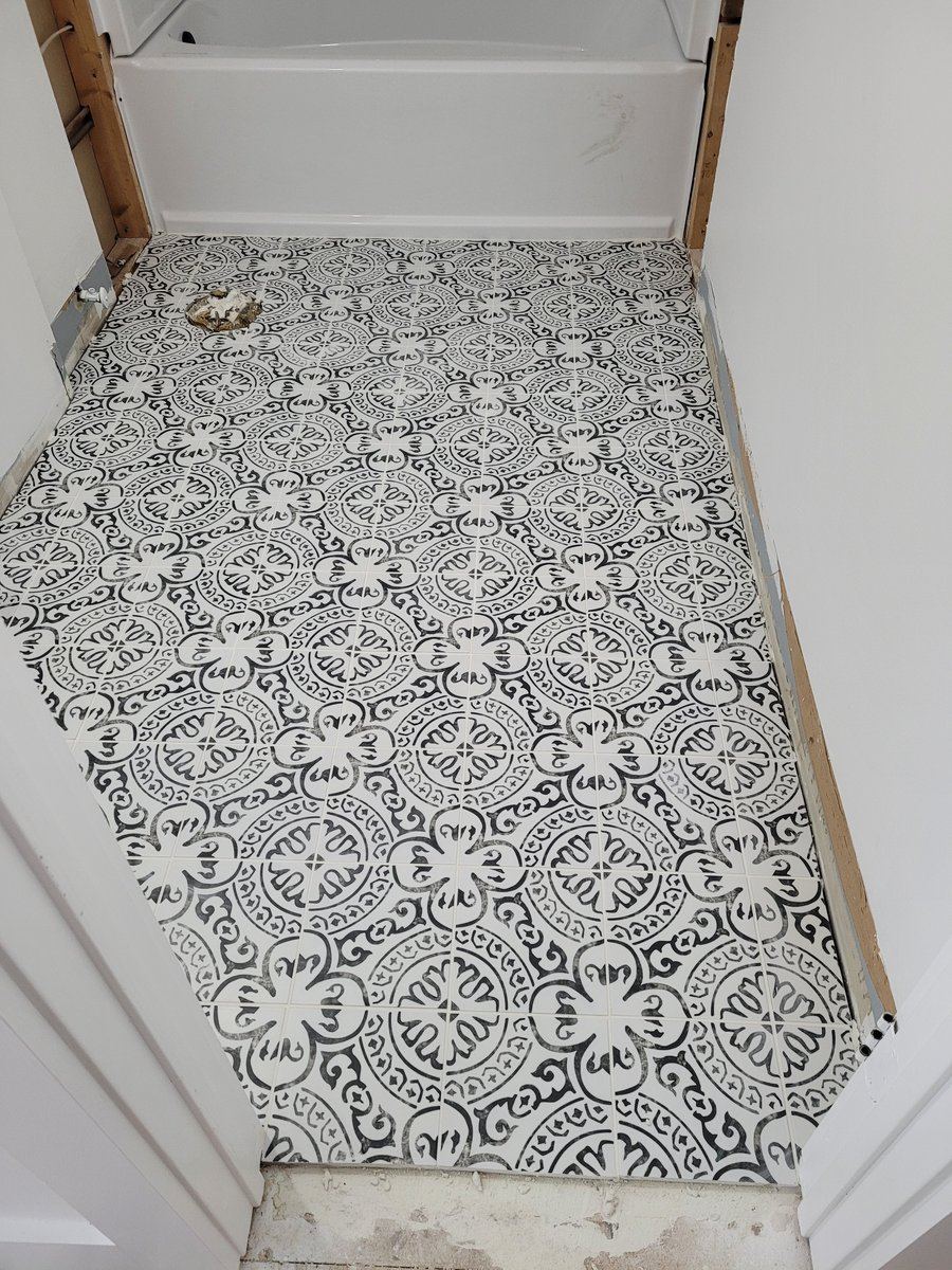 Grey wood-look ceramic tile floor and tub surround in a bathroom